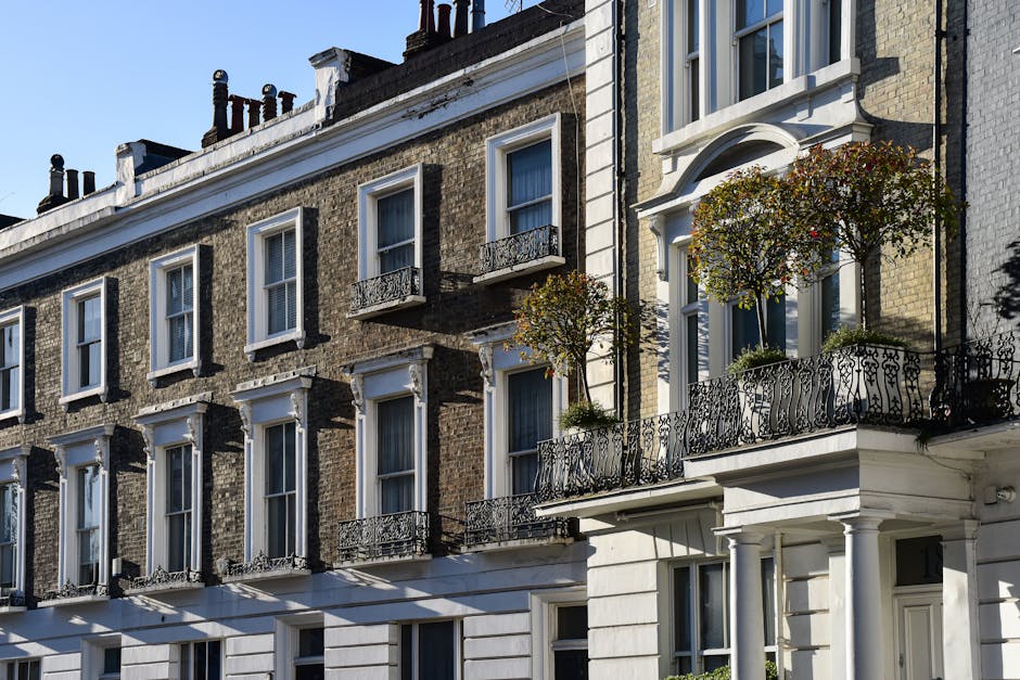 Exterior view of a historic red brick building with white decorative architectural details, including ornate window frames and cornices, situated along a city street with leafless trees and black meta